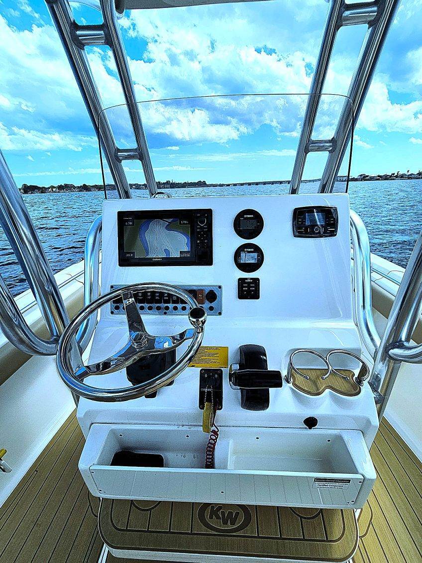 helm of a key west center console fishing boat with steering wheel, radio, navigation screen, and cupholders