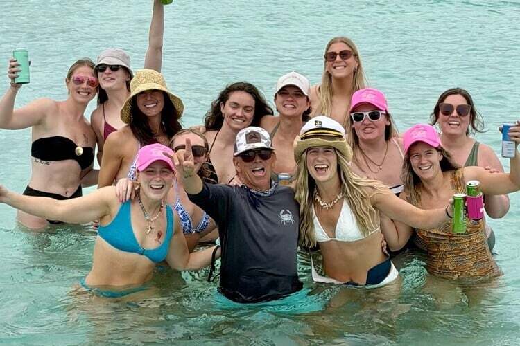 bachelorette party girls at crab island posing with captain in the water