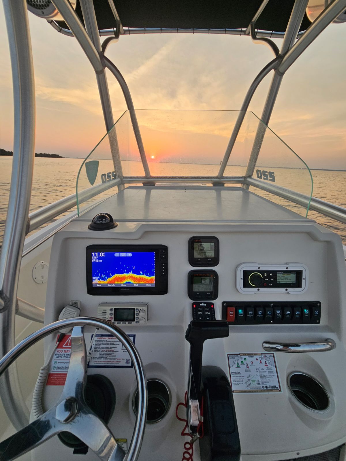 steering controls of a center console boat with sunset in the background