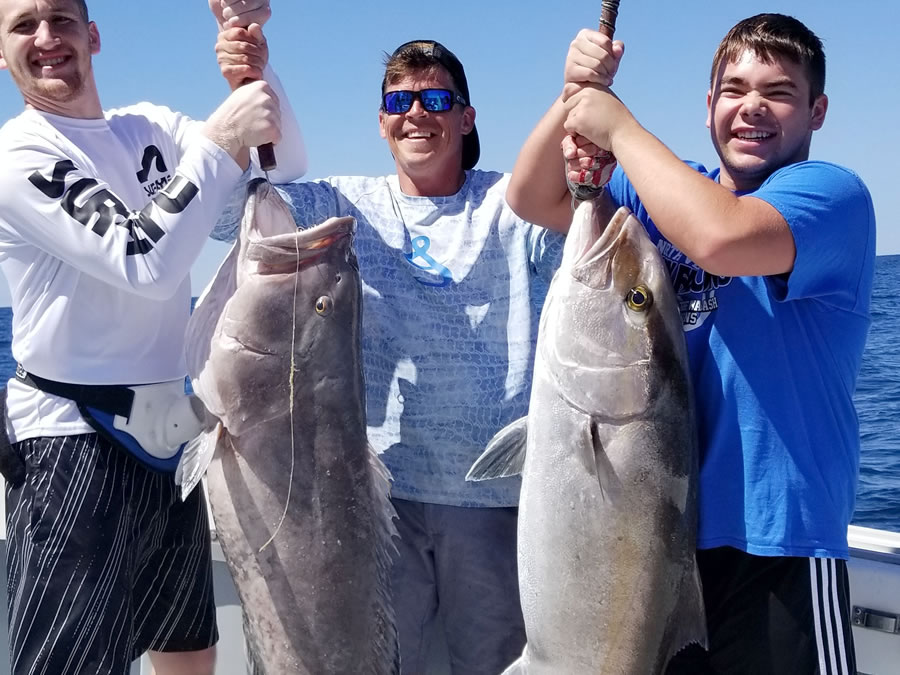 three men holding up fish they caught on their private fishing charter