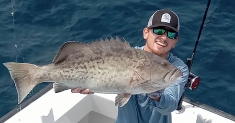 man holding up a grouper that he caught on charter boat daybreak in destin florida