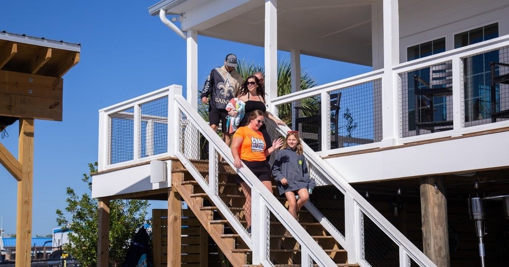 family walking down stairs of beach house to go on pontoon boat in destin florida