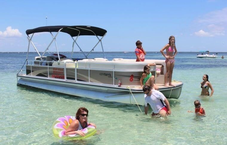 family playing in the water around a pontoon boat at crab island