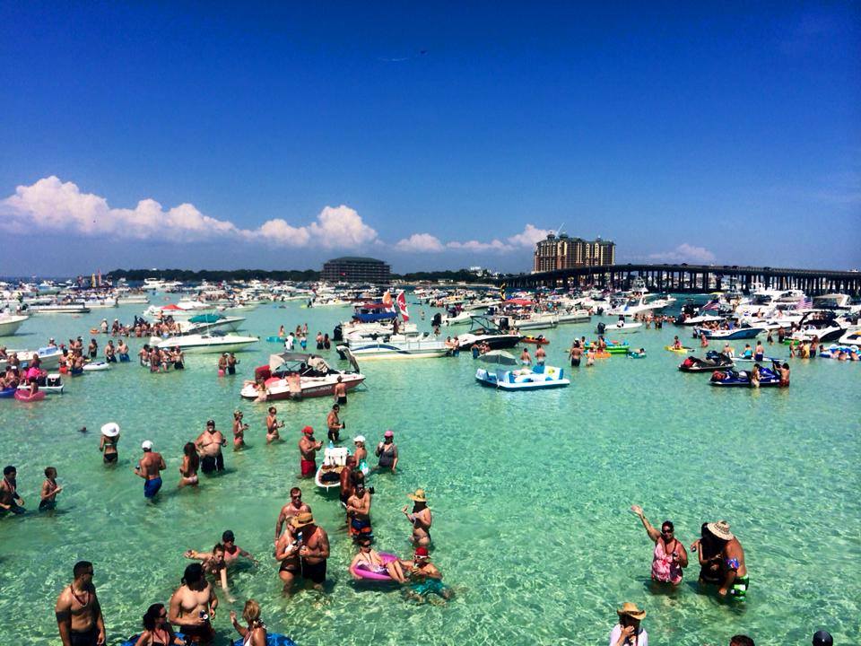 people standing in the water with boats at crab island