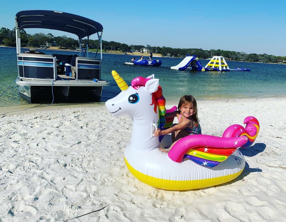 young girl on a float near a pontoon boat on the beach at fort walton beach