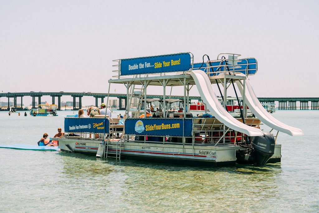 family on double decker pontoon boat with two slides at crab island