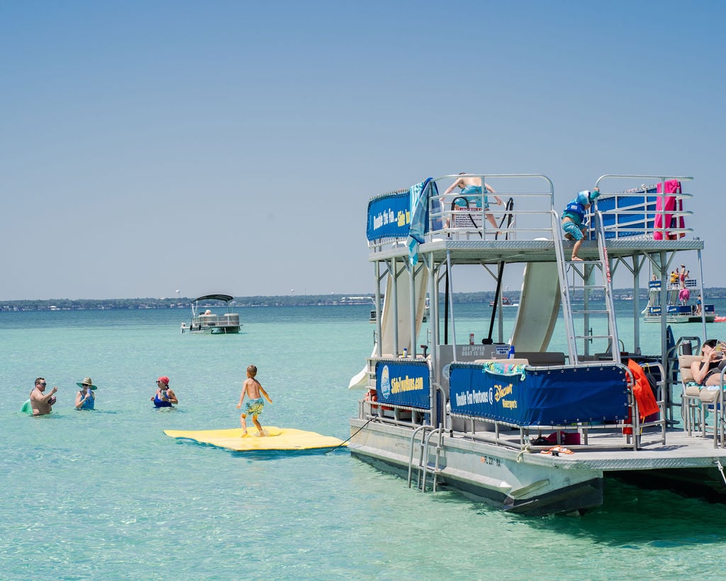 family playing on ouble decker pontoon boat with two slides in destin florida