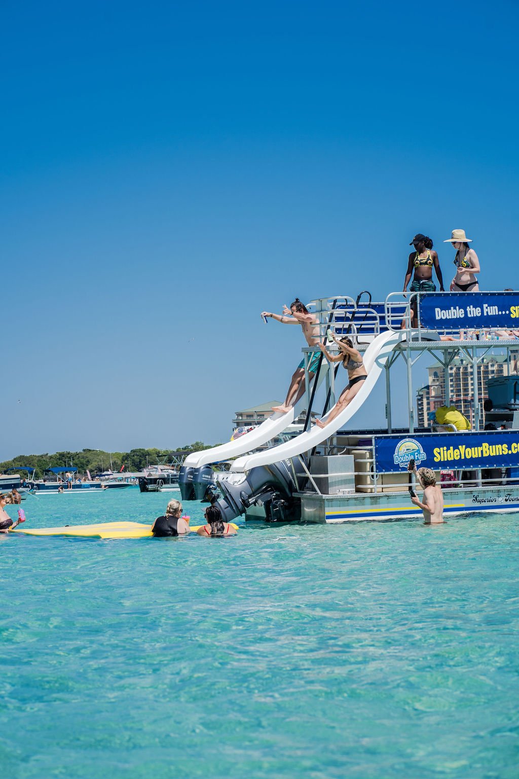 two people sliding off slides on a double decker pontoon boat in destin, florida