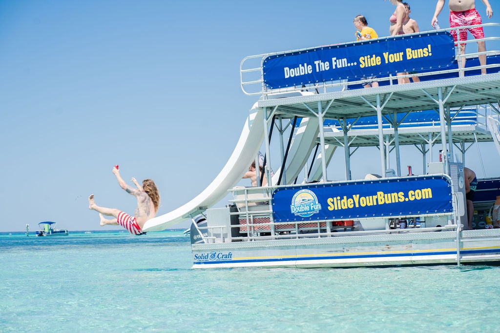 person sliding off of double decker pontoon boat at crab island