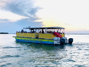 yellow tour boat driving into the sunset in destin florida