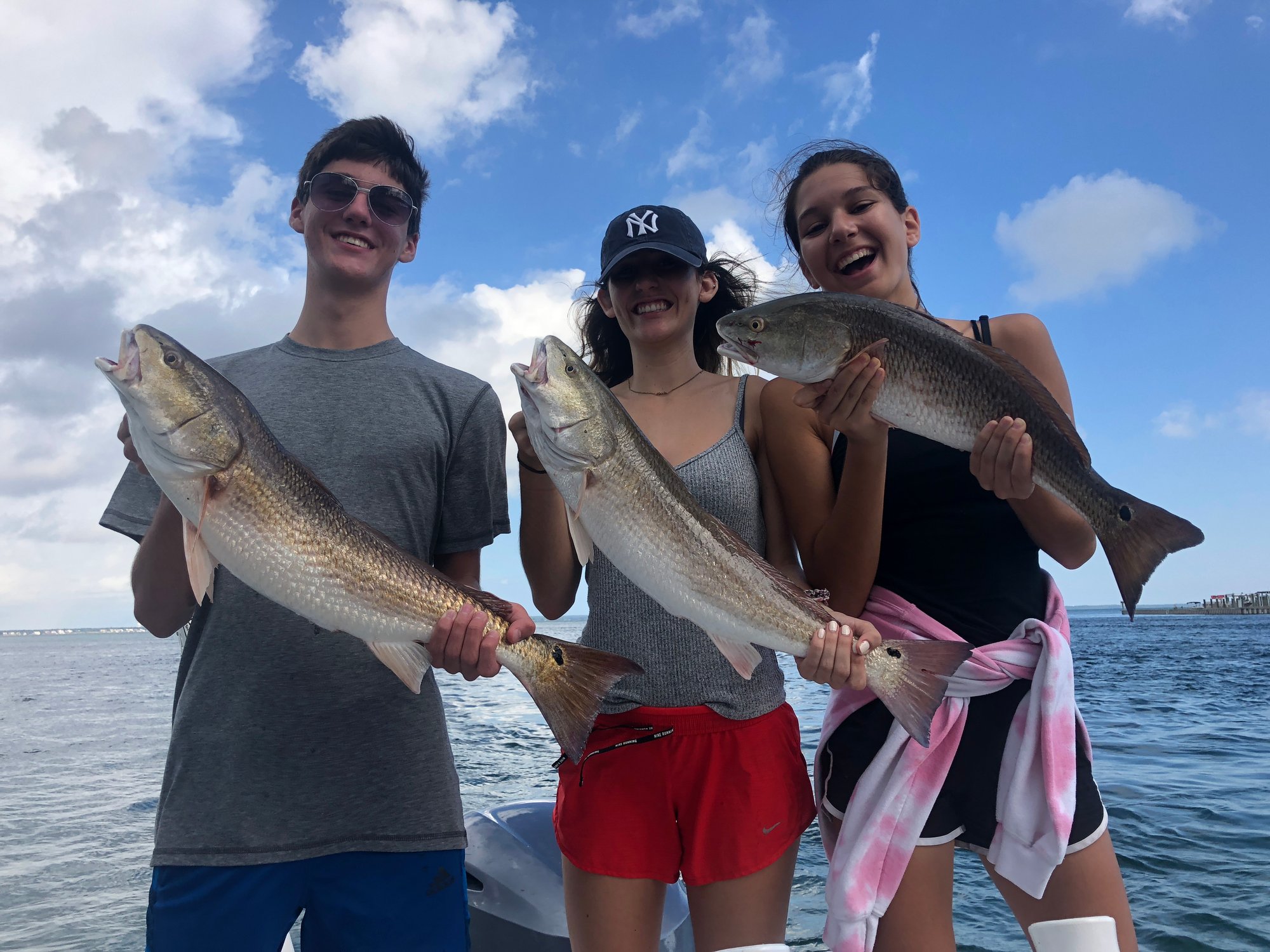 three people holding fish on a charter boat