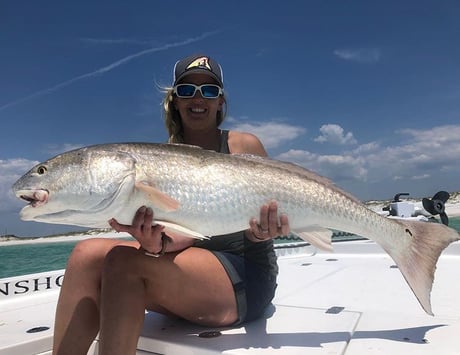 lady holding a redfish on the front of a bay fishing charter boat