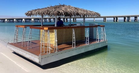 tiki boat with bar in the middle and straw roof floating in the water in destin florida