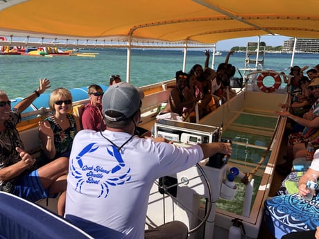 captain driving a crab island shuttle boat with a large group of people