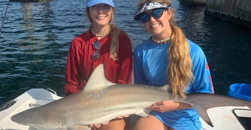two girls holding a shark on a boat in destin florida